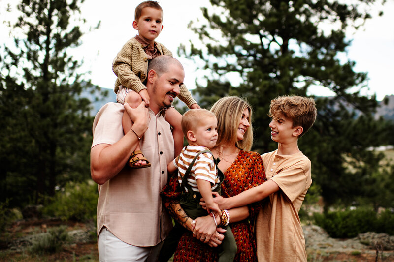 Family of 5 looking at each other with little boy on fathers shoulders at Estes Park Colorado