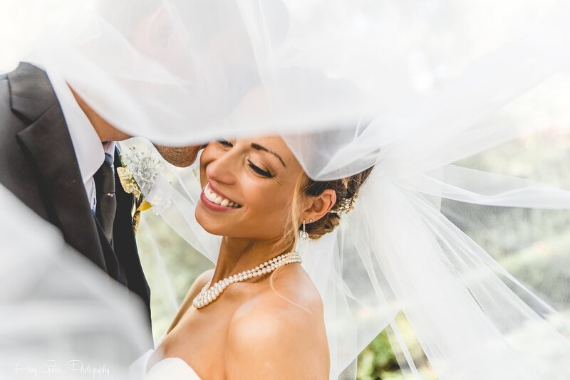 groom kissing brides forehead with her vail over both their heads