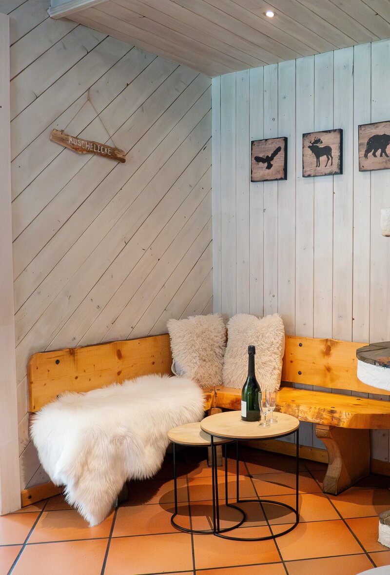 Sfeervolle woonkamer met open haard, comfortabele banken en rustieke houten afwerking in Haus Arlberg.