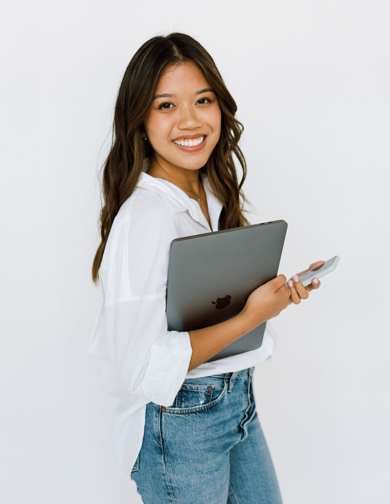 Woman holding laptop and smiling at camera