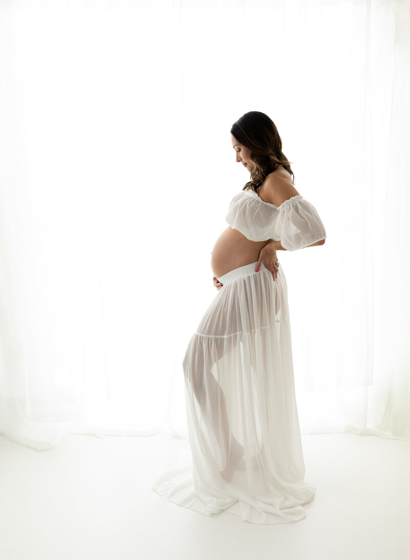 pregnant mother in white maternity dress holding baby bump Cleveland family photographer