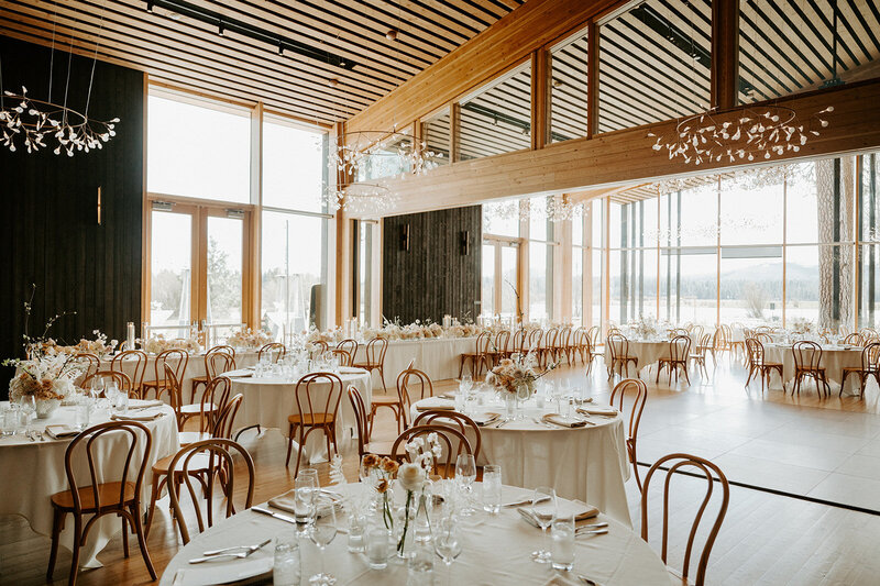 Reception tables with lucite vases of white and neutral-toned florals, pale Bentwood chairs, and candlelight at Jenay and Daniel’s modern romantic wedding, by Summer Robbins Flowers in Central Oregon