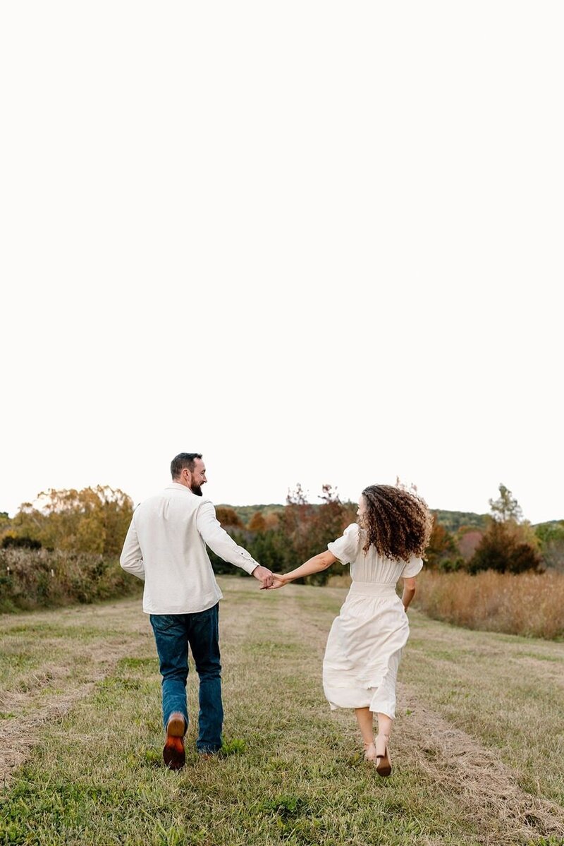couple holding hands and running during engagement session in virginia