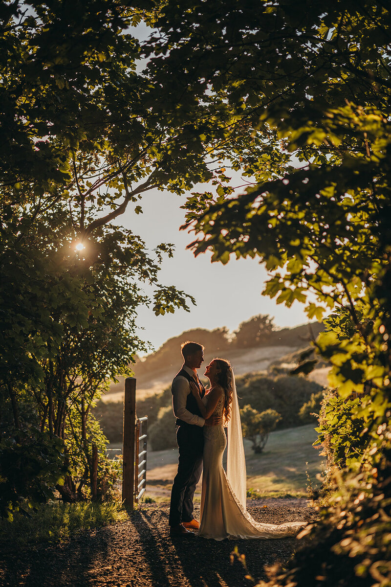 bride and groom underneath veil at sunset