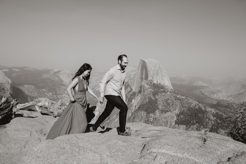 man and woman walk along cliff edge on flat rocks