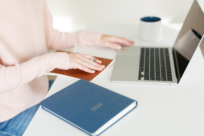 Woman with a pen placing her hand on a closed journal