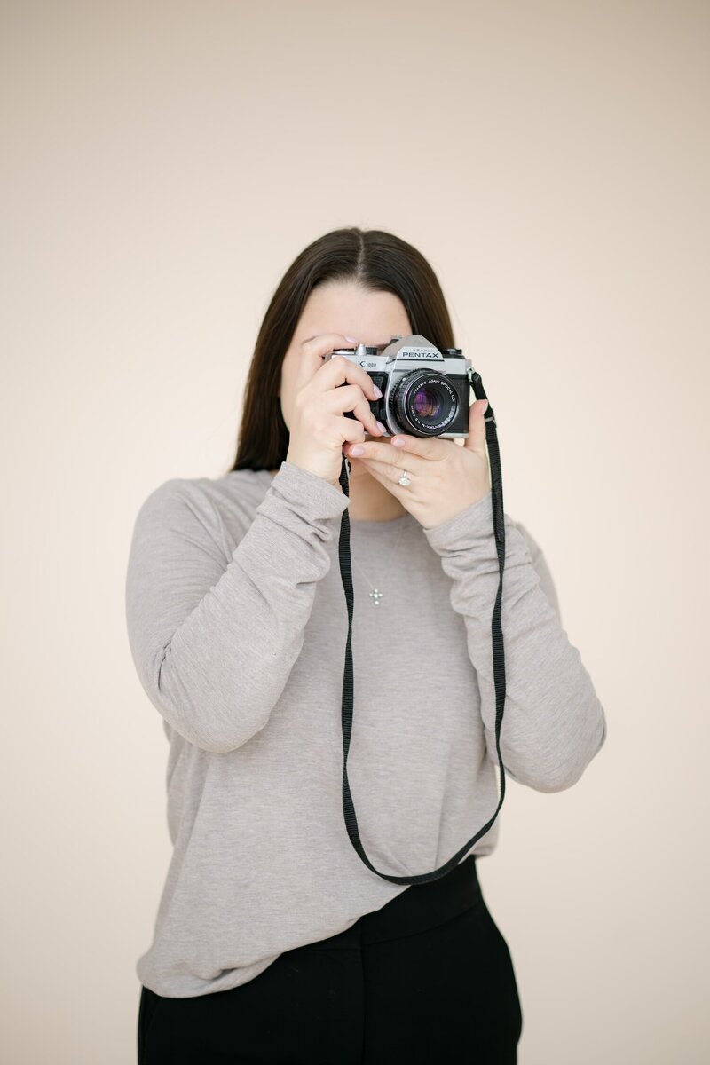 Ephe holds a 35mm film camera up to her eyes to take a photo.