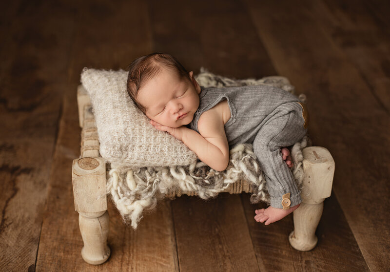 Newborn baby boy posing on bed in studio. Captured in studio by Candice Berman Photography.