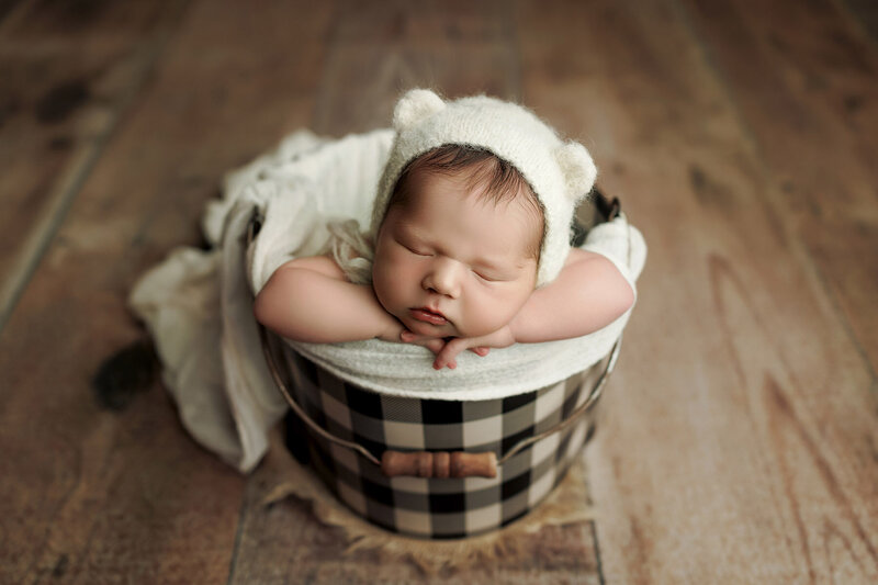 Newborn baby girl in a  daisy bucket for newborn pictures in fort collins.