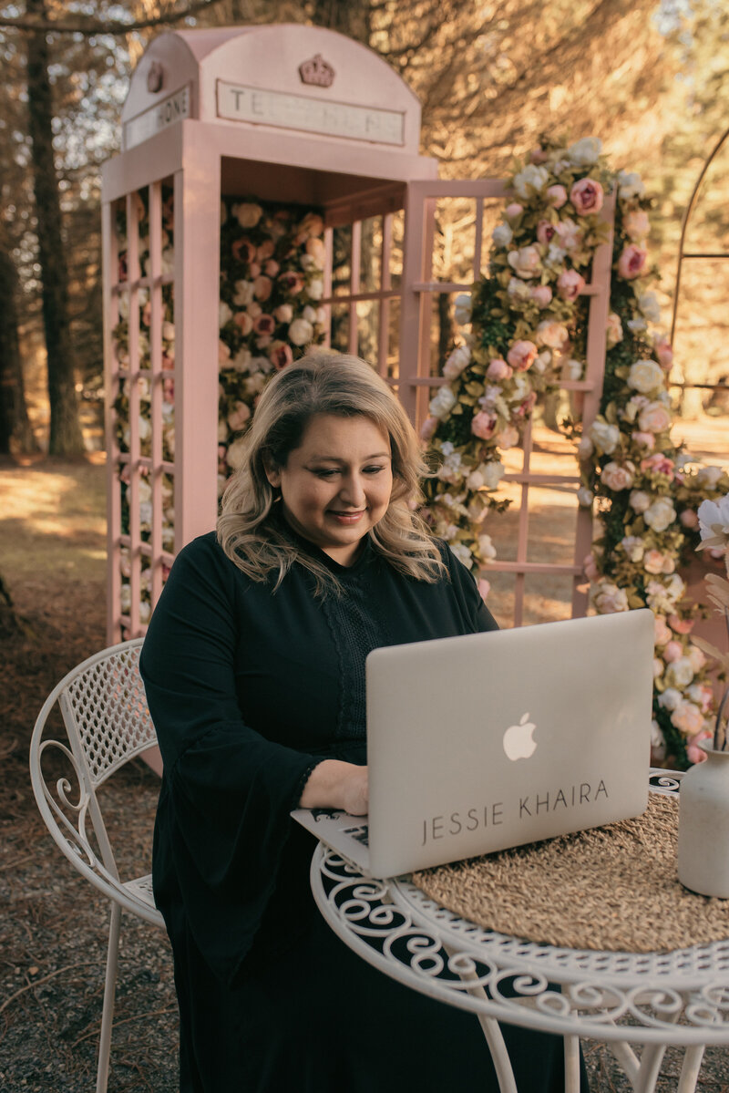 luxury sikh wedding planner smiling at her desk in front of her laptop