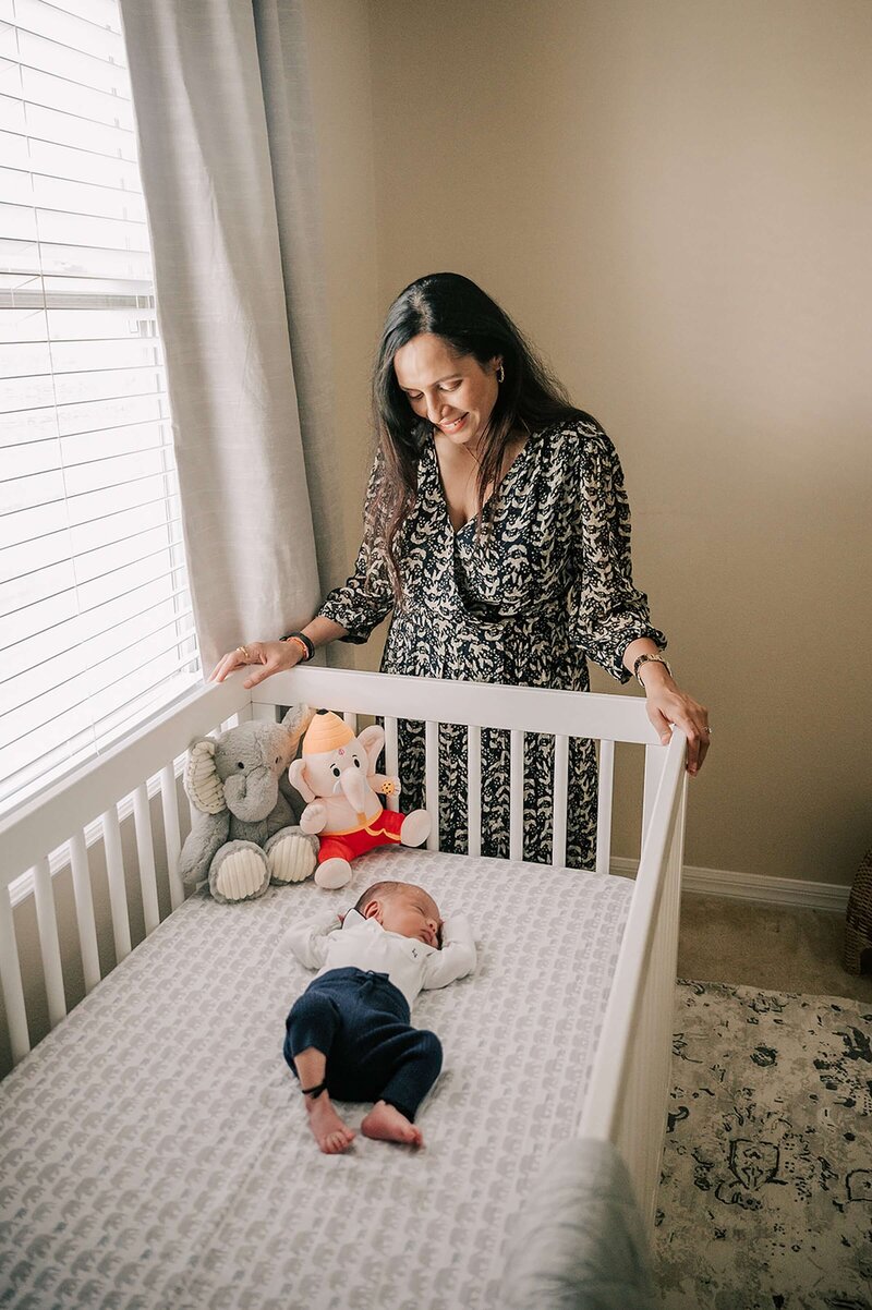 New mom looking at newborn son in crib in Orlando FL