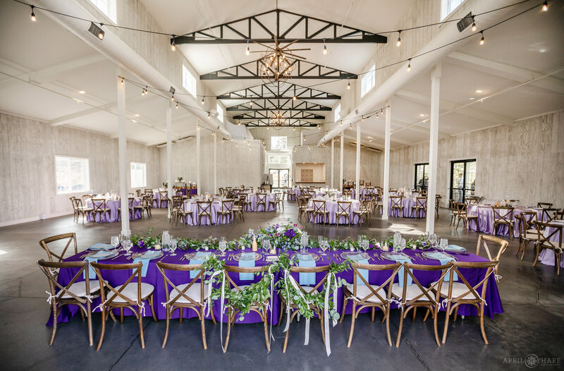 Interior of The Woodlands Barn set up with purple decor for a Wedding Reception Dinner in Conifer Colorado