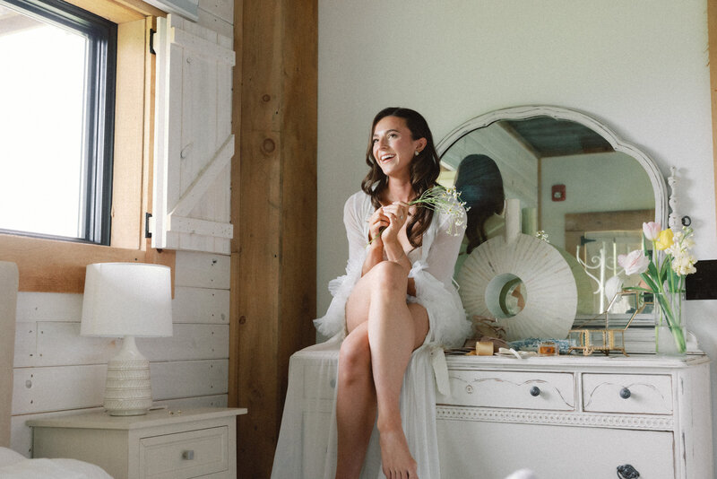 Bride getting ready in a bright, rustic-chic room with whitewashed walls, natural wood beams, and vintage decor at Bear Ridge Destination.