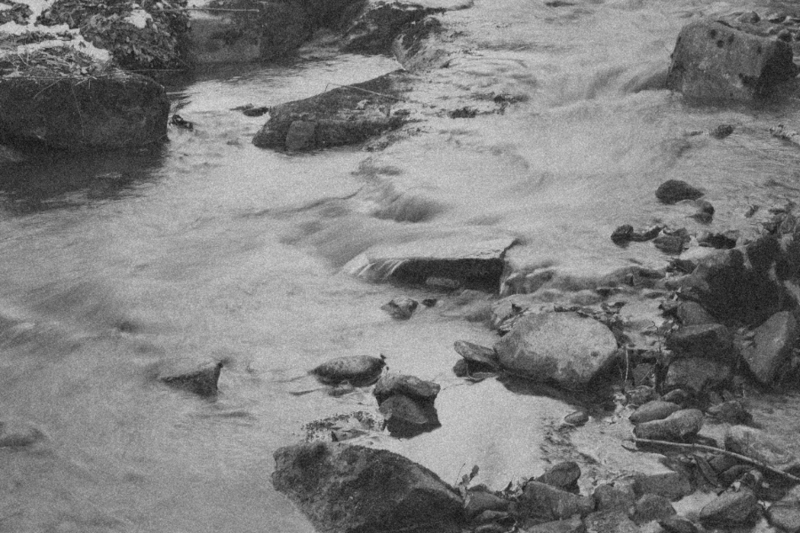 Clear water rushing swiftly through a creek bed, capturing the fluid, dynamic energy of the LIMINAL Directional Calling in CPTSD Medicine—symbolizing emotional release, surrender, and courageously crossing thresholds into empowered new beginnings.