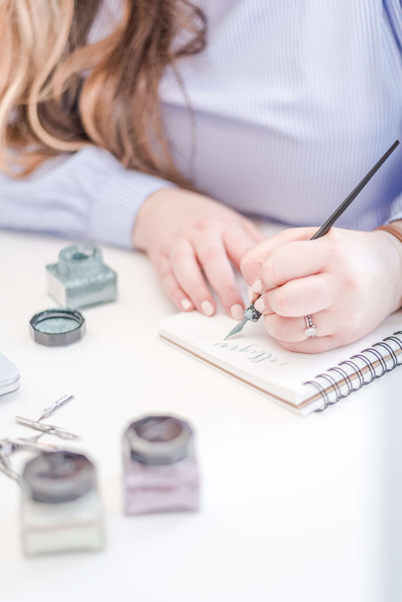 Elyse Stokes writing hand-lettered modern calligraphy in her signature style, using a calligraphy pen and nib