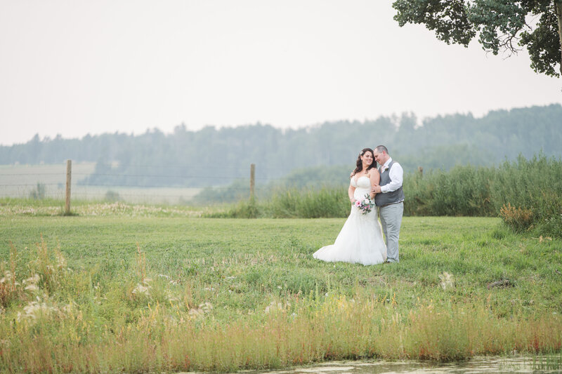 couple at sunset getting wedding photos by pond