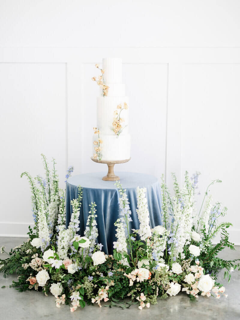 Cake on stand on a table surrounded by floral arrangement by event planning minneapolis.