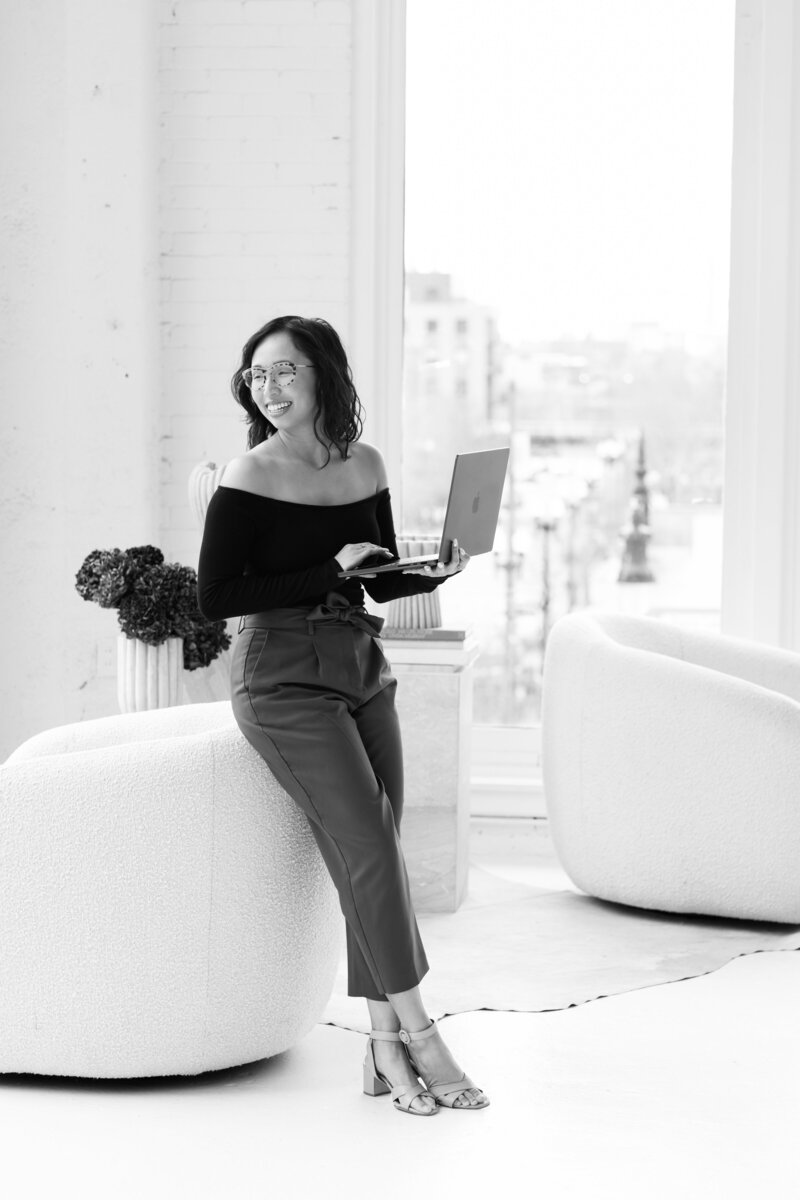 Anh Nguyen, photographer, editing photos on a computer smiling.