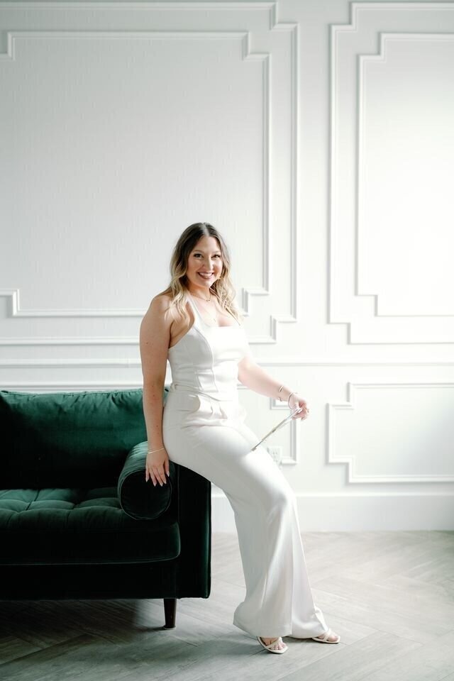 Wedding planner in Houston leaning on a green couch.
