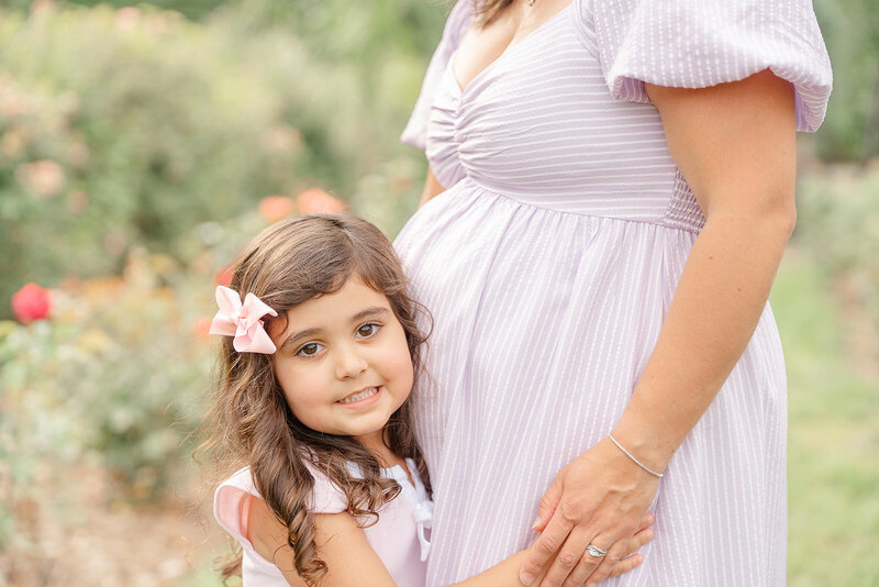 big sister hug mom's belly at a park in Warrenton, VA