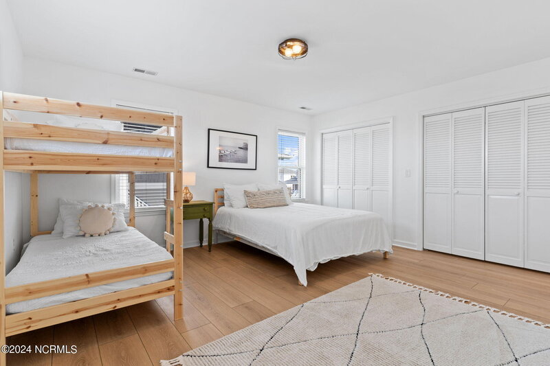 Guest room with one bed, bunk bed, olive green shared nightstand, stylish rug, and warm, inviting decor.