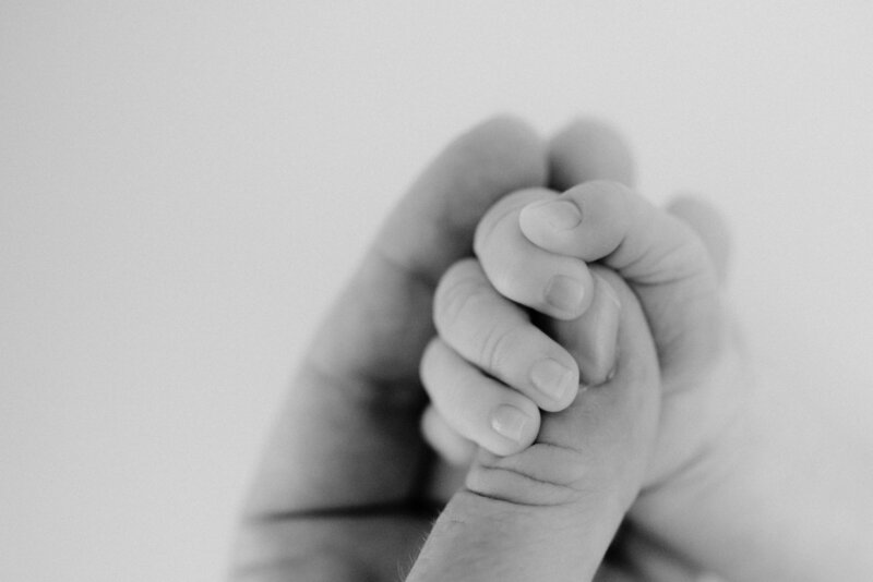 Newborn holds mothers thumb