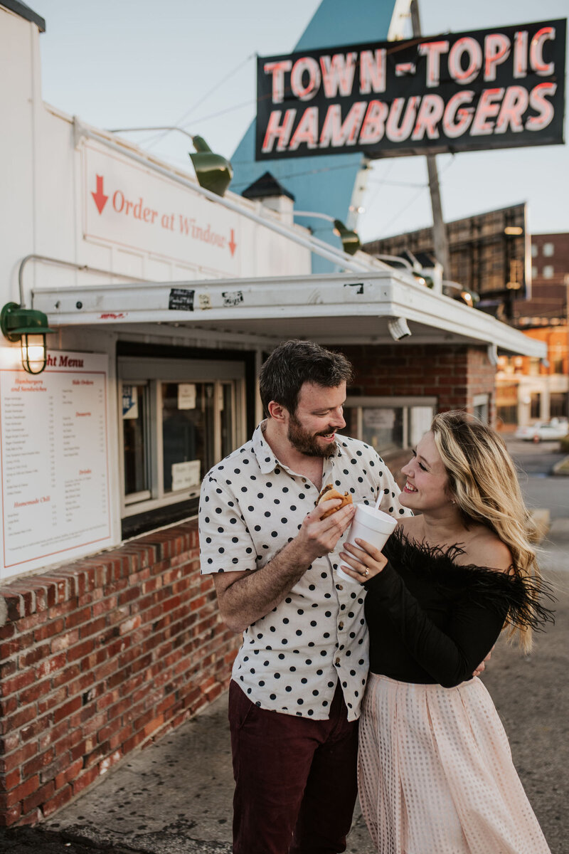 a couple having a burger and shake in front of a retro diner