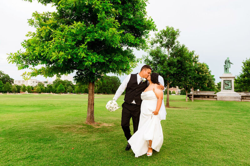 Wedding couple walking together and sharing a fast kiss in Centennial Park