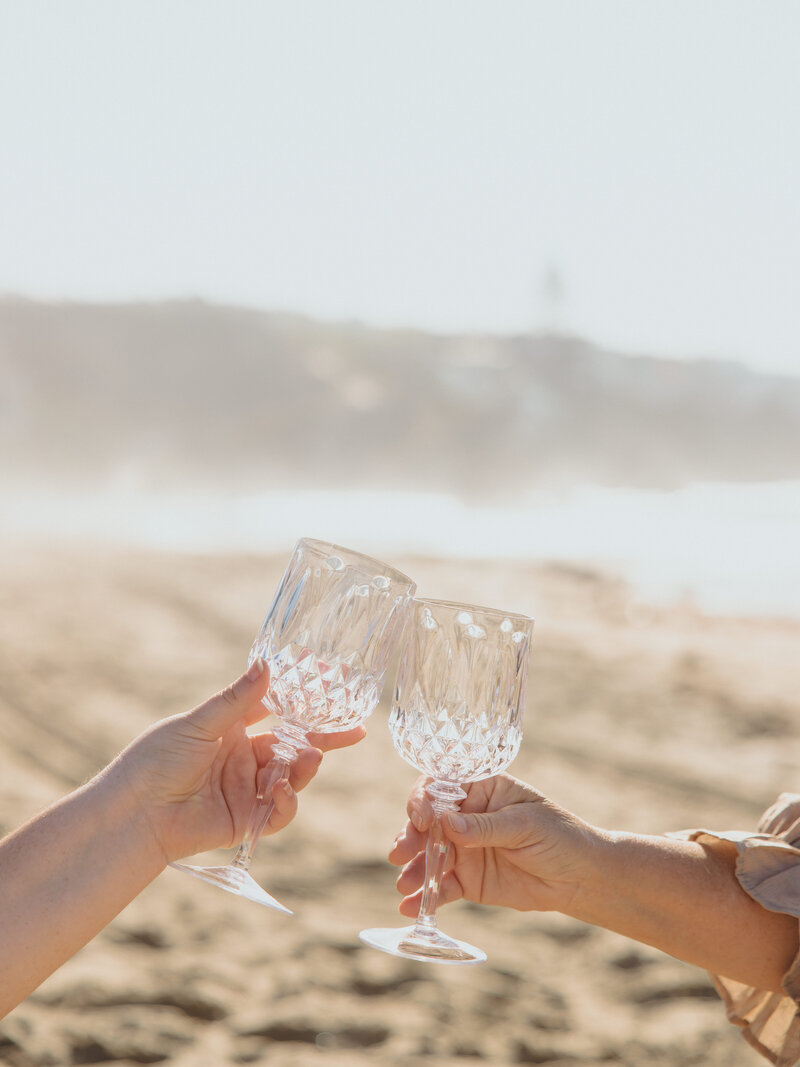 Glass goblets toasting on beach
