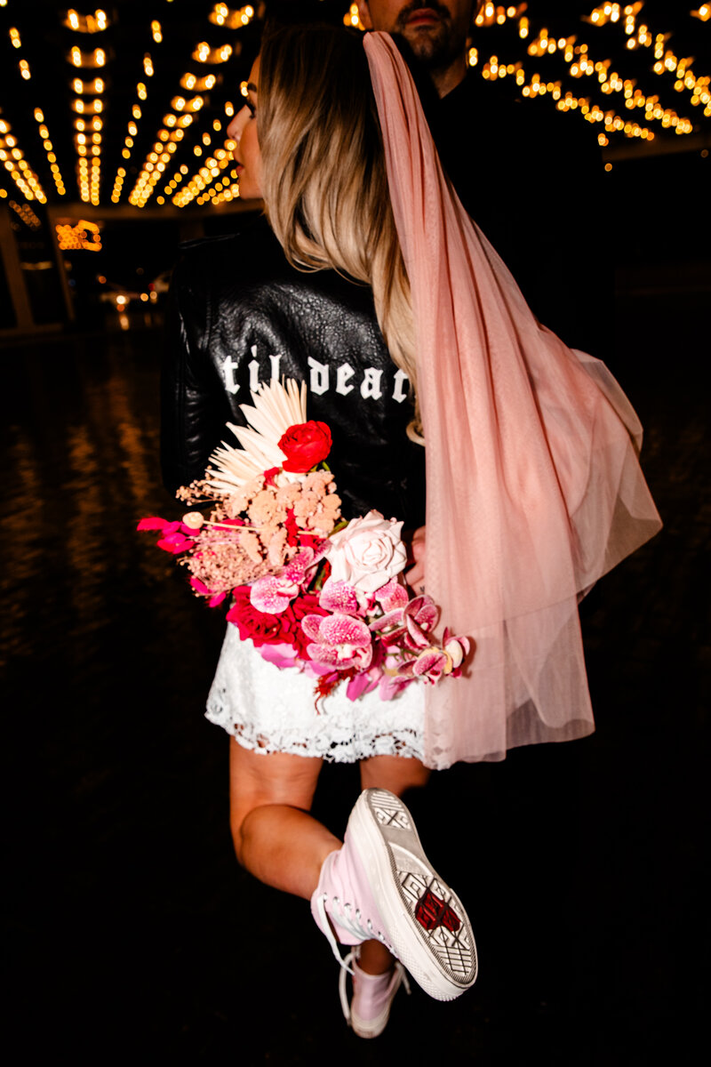 a pink and red bouquet next to a black leather jacket that was painted with "til death"