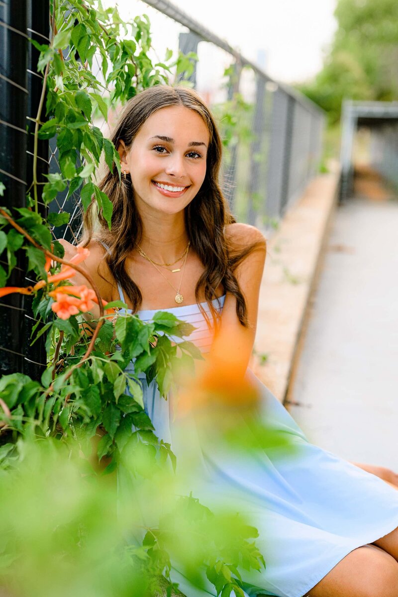 orange flowers and vine are in the foreground of images containing charlotte graduate in blue dress
