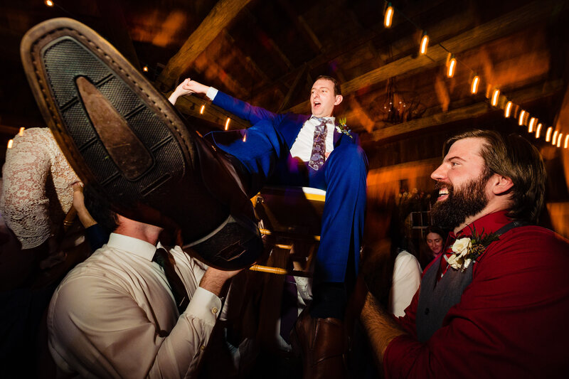 A groom is hoisted up in a chair during the reception