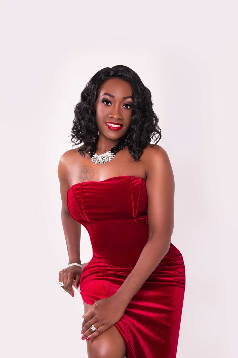 An African American woman in a red dress sits in a chair.