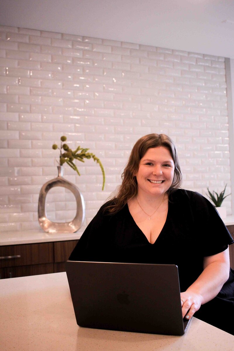picture of a woman sitting at a desk with a laptop in front of her