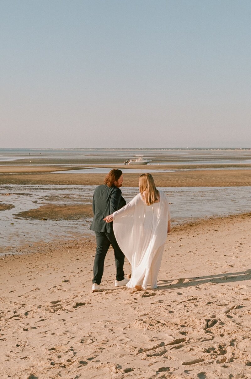 35mm film photo of a couple walking along the Cape Cod shoreline during their summer micro wedding — a quiet, romantic moment captured by a film wedding photographer.