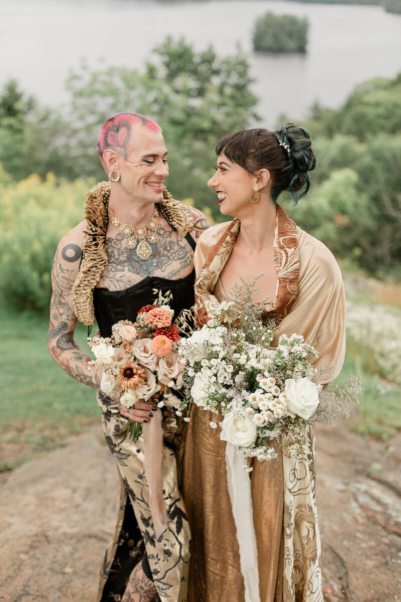 A couple hold bouquets and smile at each other after their elopement ceremony