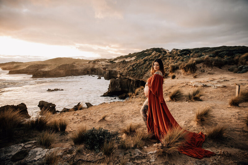 Pregnant woman stands on cliff top in red gown for Melbourne Maternity  session