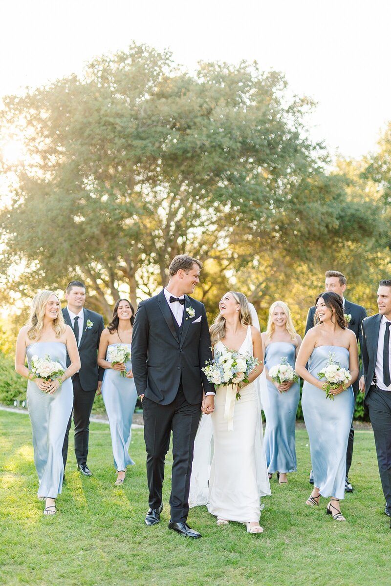 Bride and groom walking with bridesmaids and groomsmen on the grounds of Rancho Valencia in Rancho Sante Fe, California.