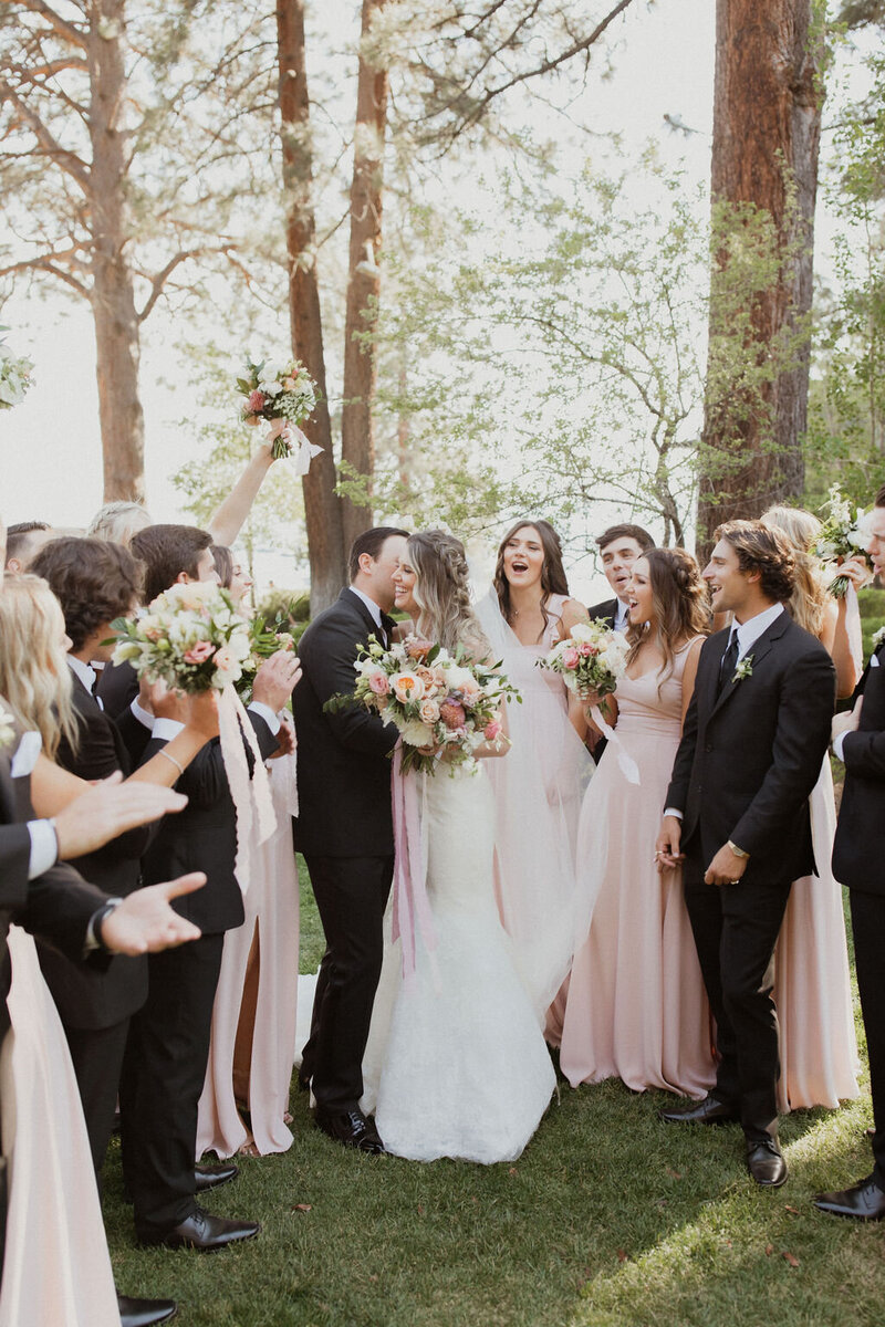 groom kissing bride while surrounded by bridal party