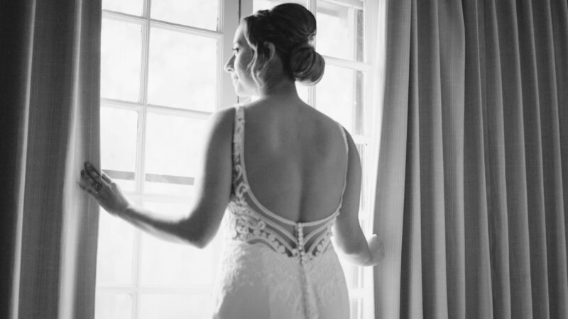Bride looking out the window, captured in an emotional moment before the wedding ceremony by Super 8 wedding videographers, Tyler and Makenzie Films.