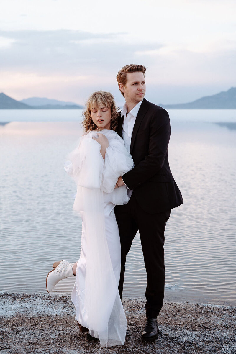 Far landscape shot of couple holding eachother during sunset during a Bonneville Salt Flat Elopement