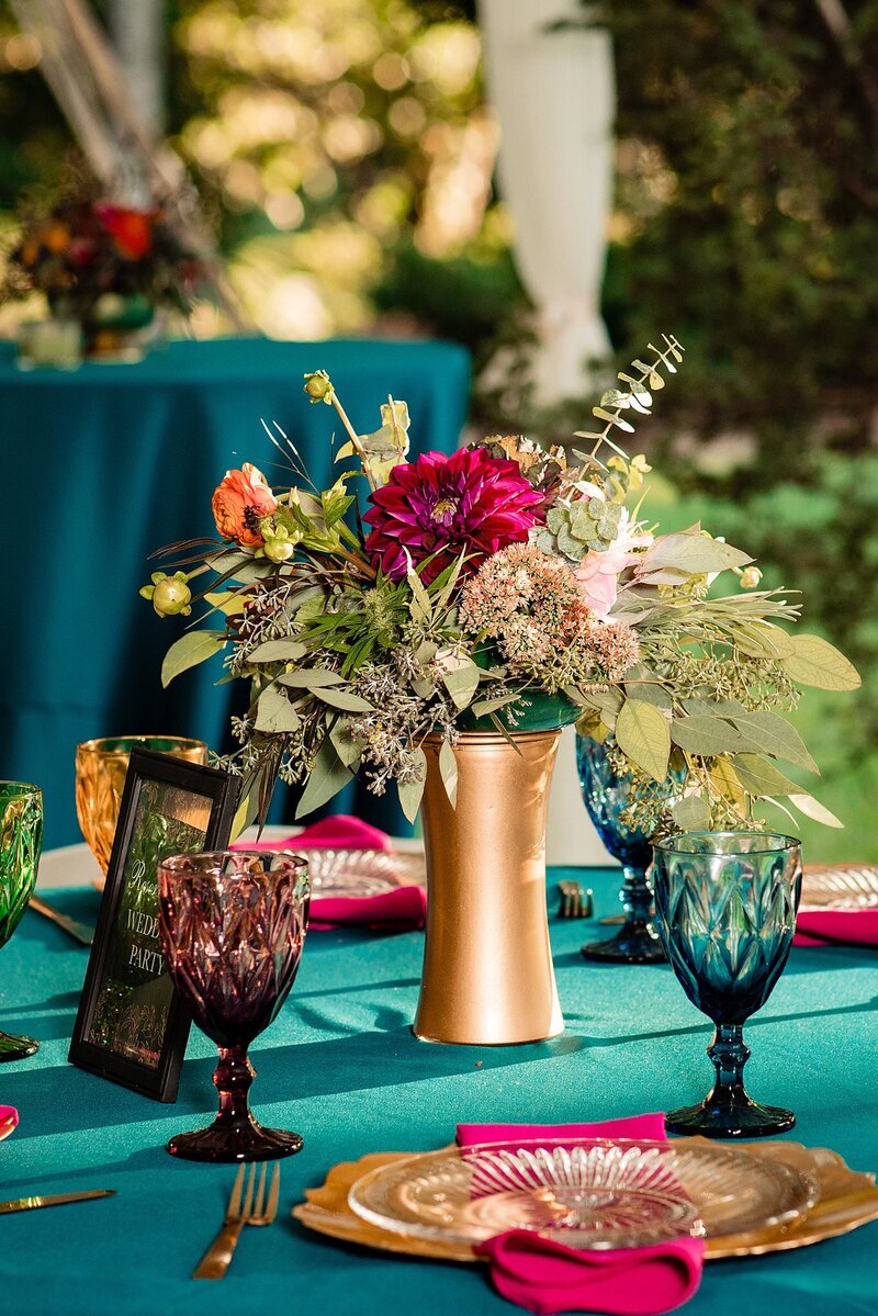 Bright gold vase filled with colorful flowers, teal and pink decor