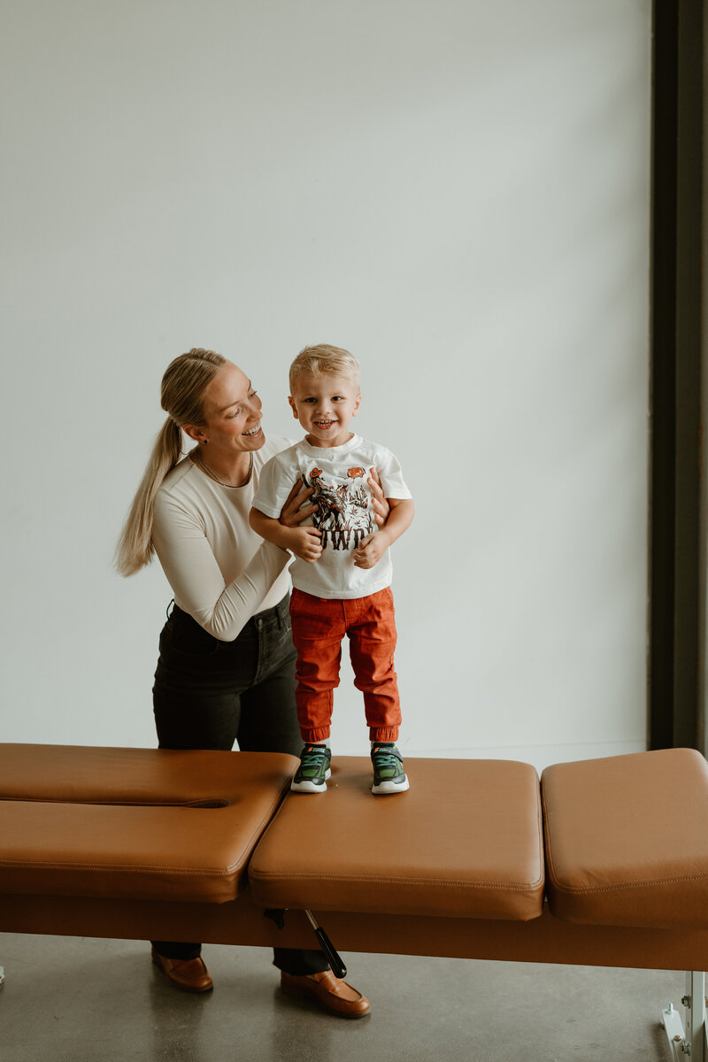 Woman holding child on chiropractic table