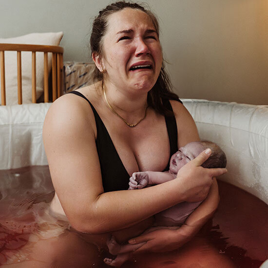 mother cries after birth holding her newborn