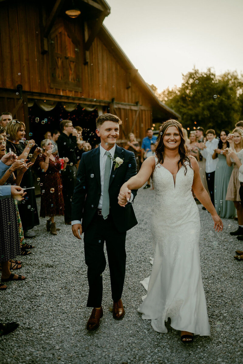 Bride and groom happily doing their wedding exit with bubbles