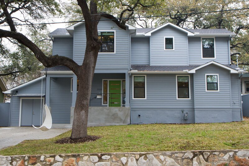 two story home with green accent door in austin, texas. grey siding home.