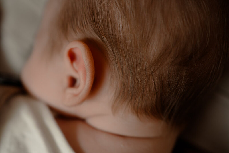 Baby wordt gedragen op papa's armen en moeder heeft handen rondom zijn hoofdje.