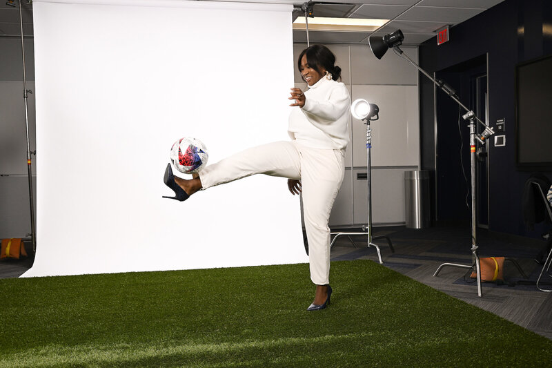 Chioma Atanmo kicking soccer ball in heels