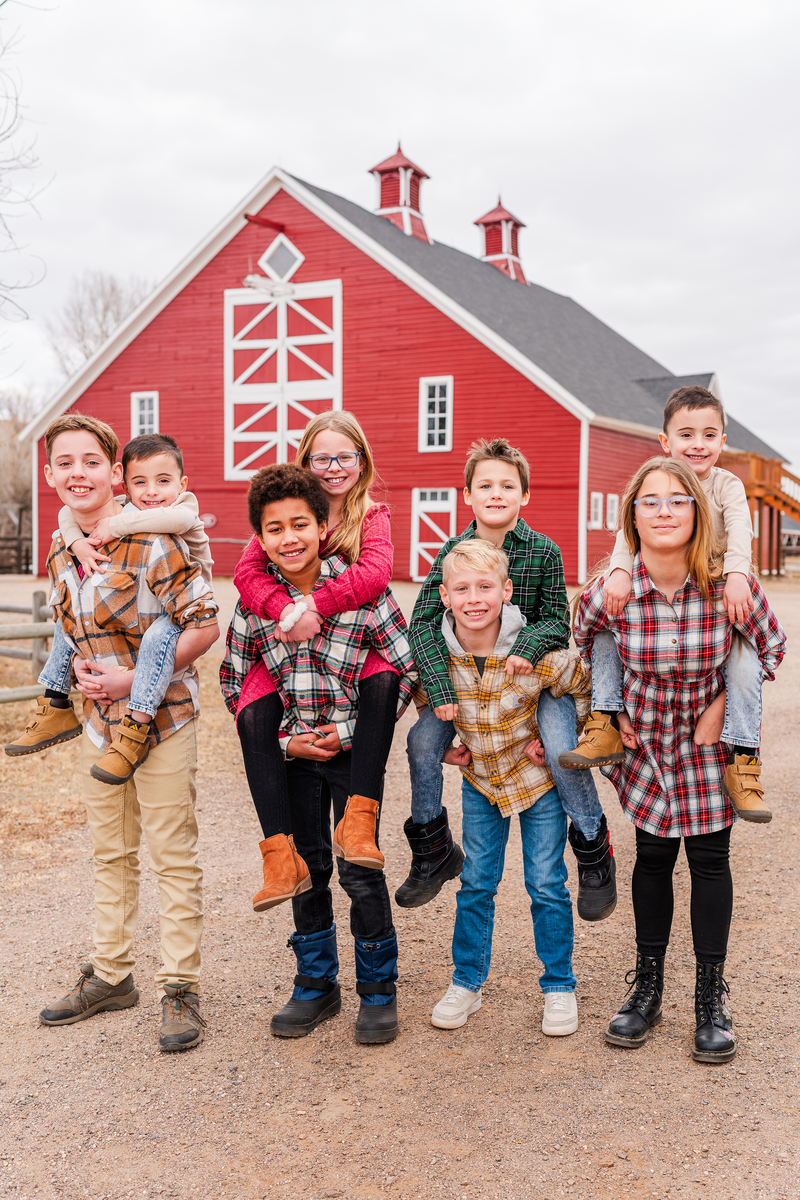 family photo of children in front of red barn