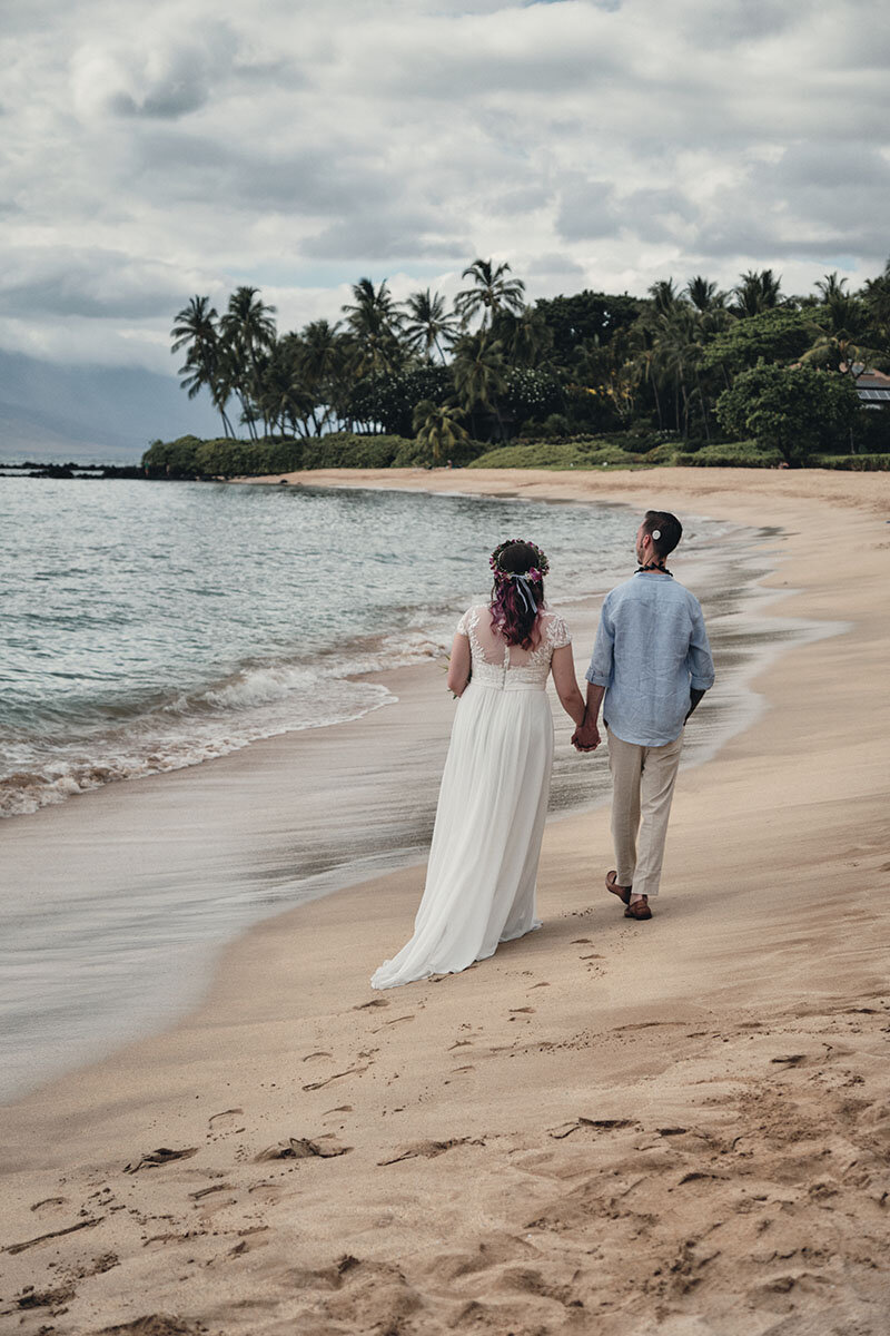 Eloping couple walking hand in hand on the beach